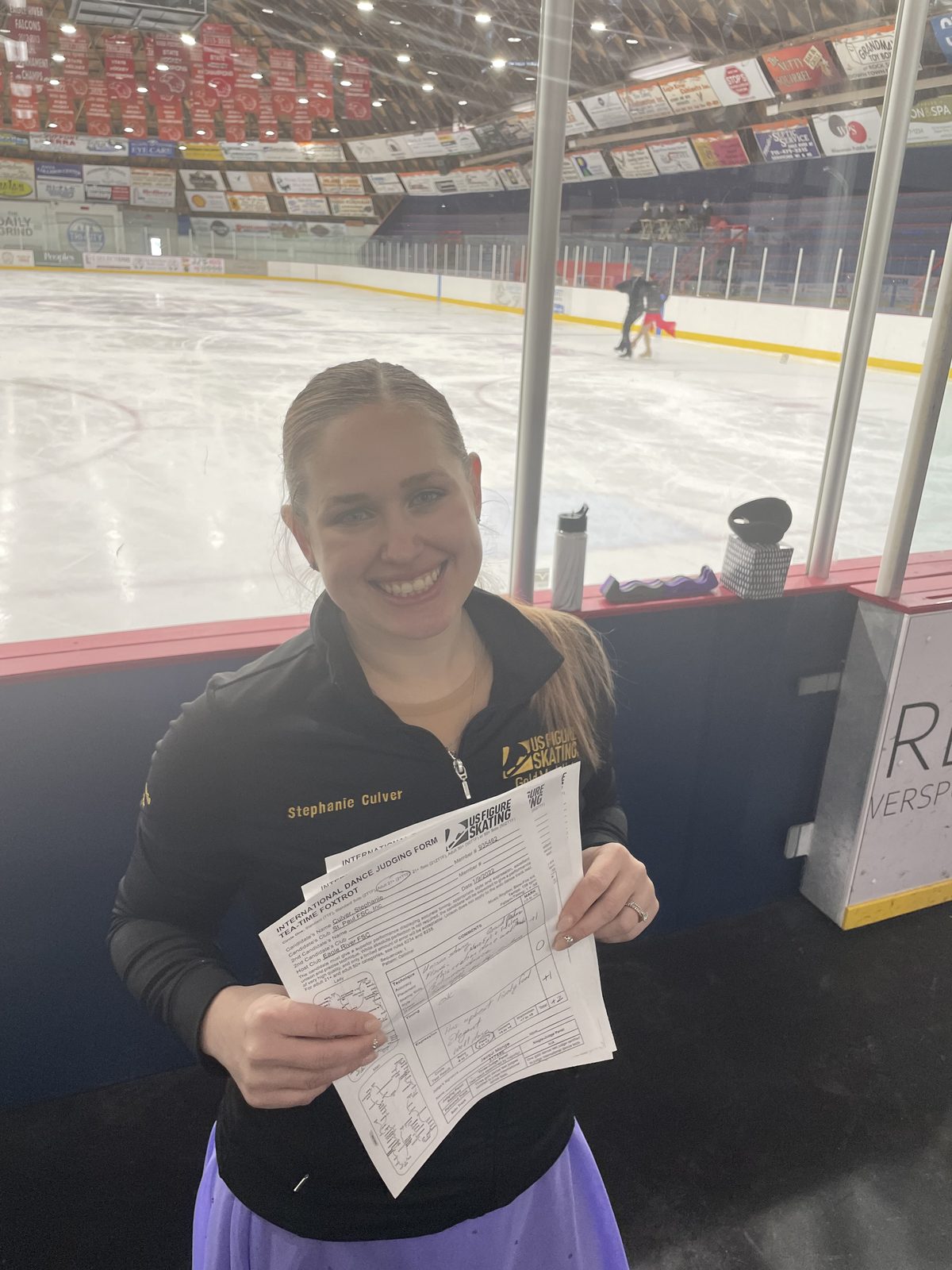 Stephanie Culver reviewing evaluation materials rinkside — coaching and judging context